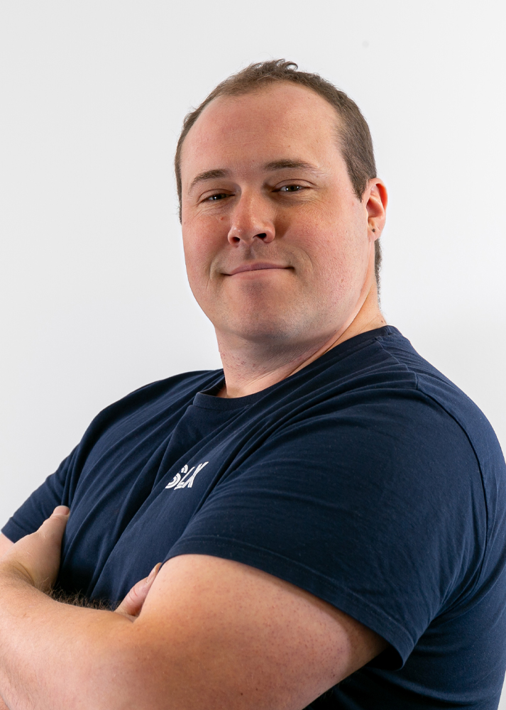 Casey Howell Project Manager at SLX with his arms crossed on a white background