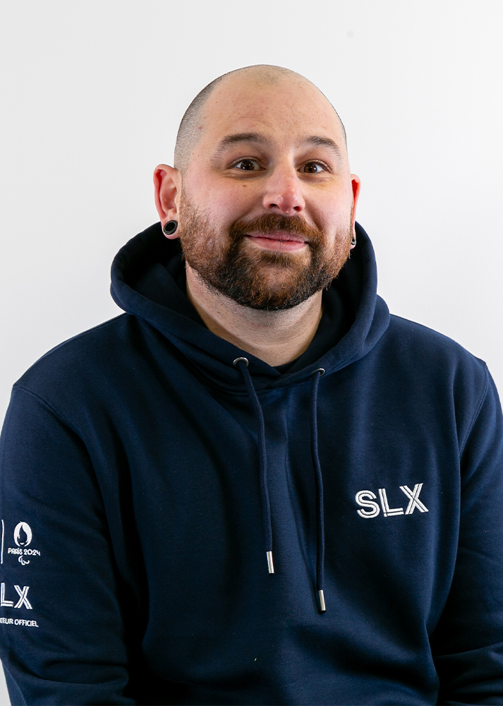 Matthew Trawford SLX Moving Lights Technician looking to the side smiling on a white background